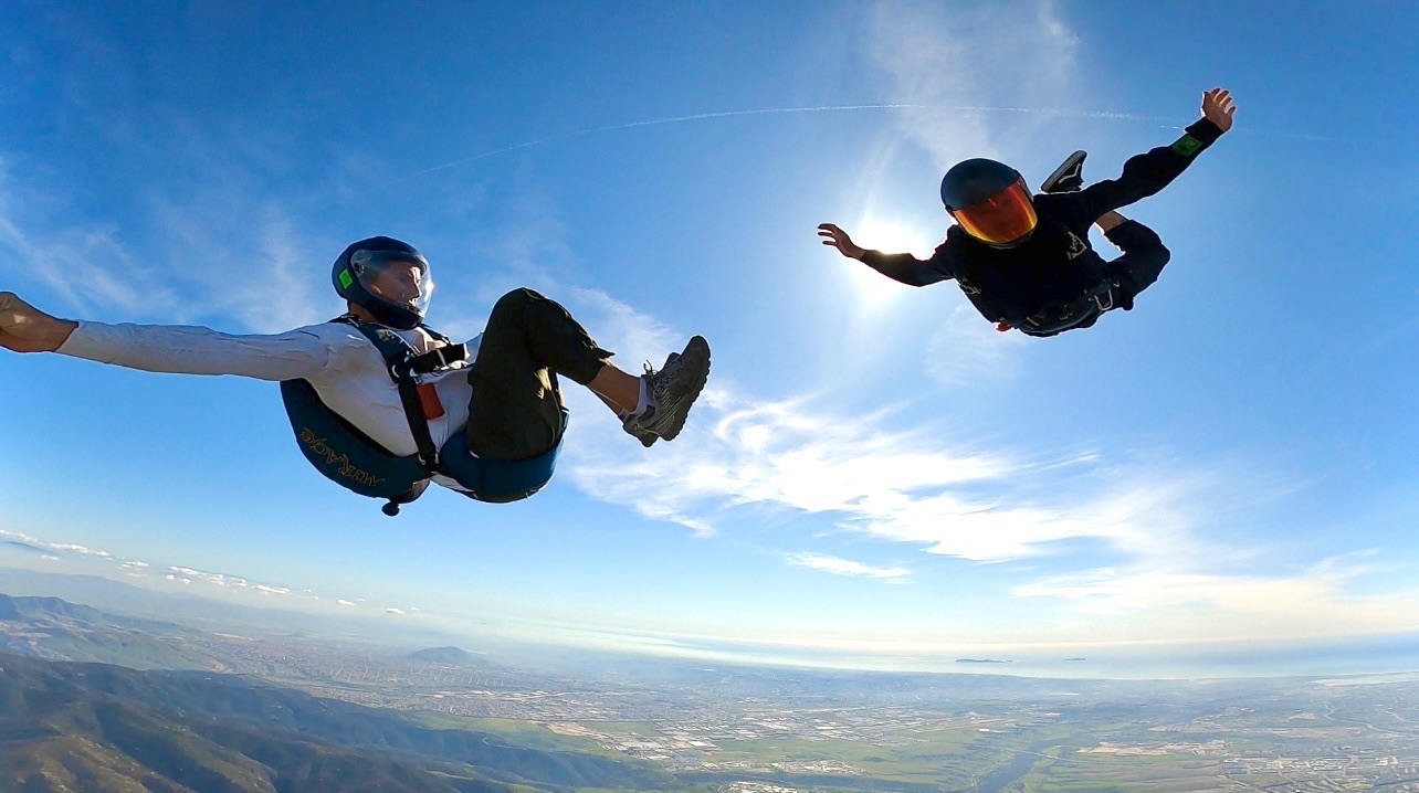 Two skydivers in free fall high above the coastline