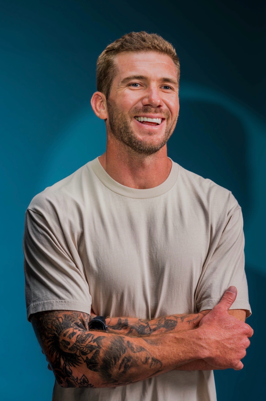 Charles in a light T-shirt, smiling with his arms crossed