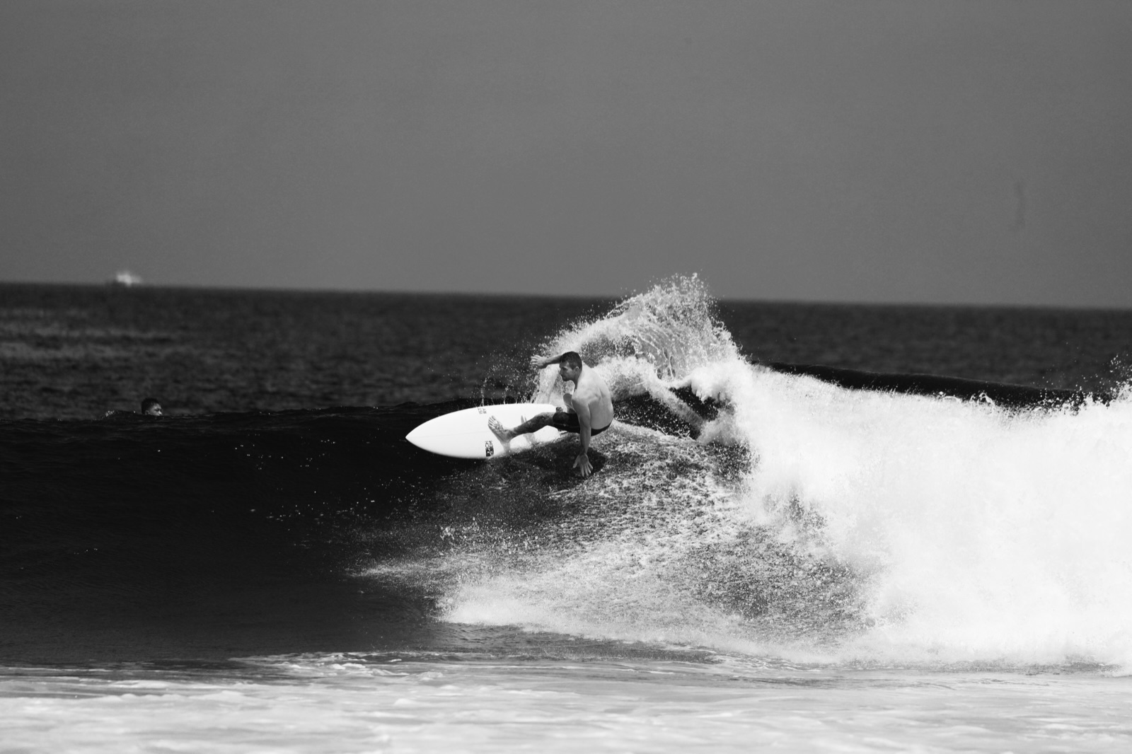 Black-and-white photo of a surfer carving across a wave